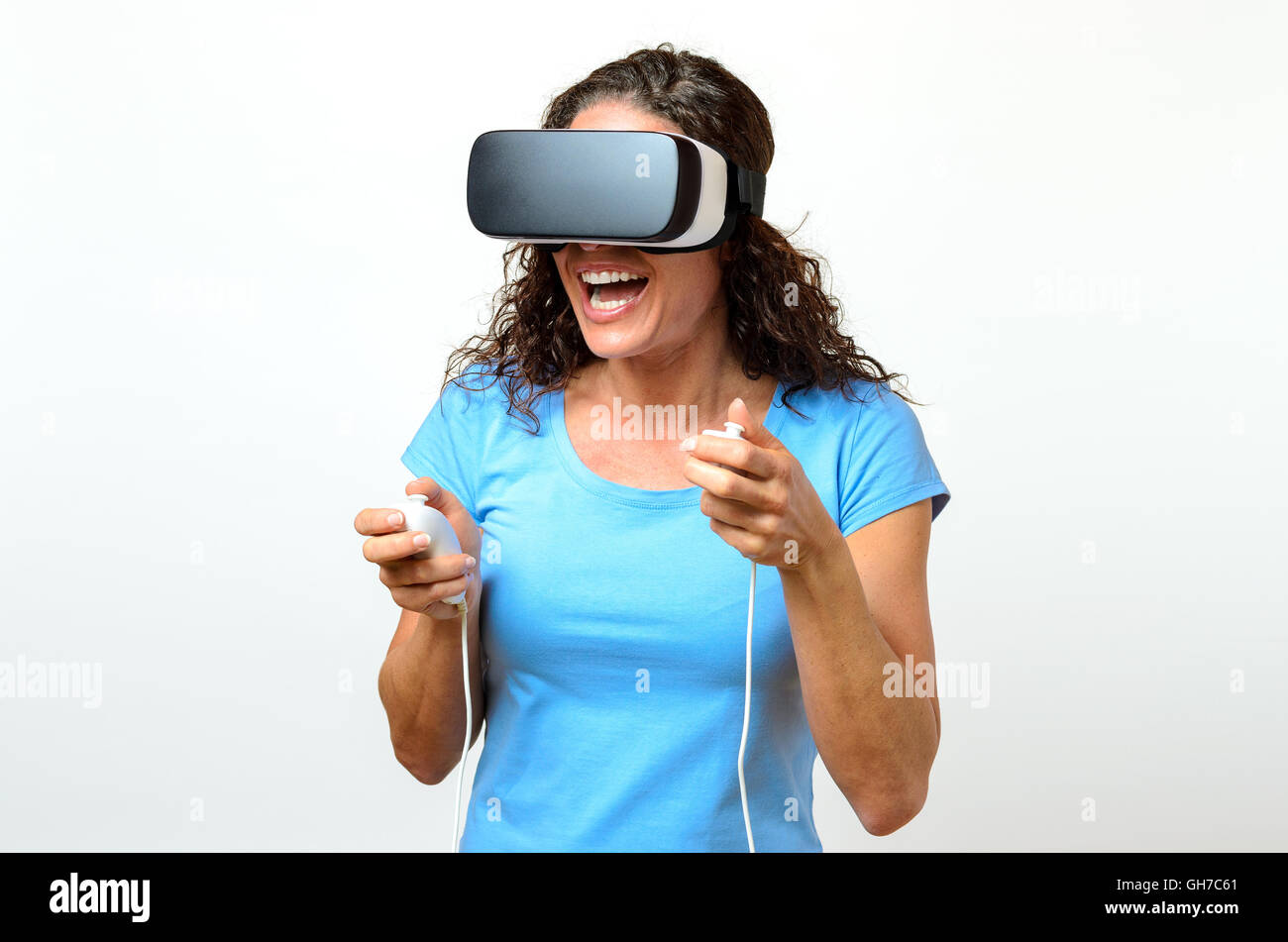 Seul rire jeune femme en chemise bleu et des cheveux sombres grand port de réalité virtuelle en 3D de l'appareil de visualisation sur le visage et le controllin Banque D'Images