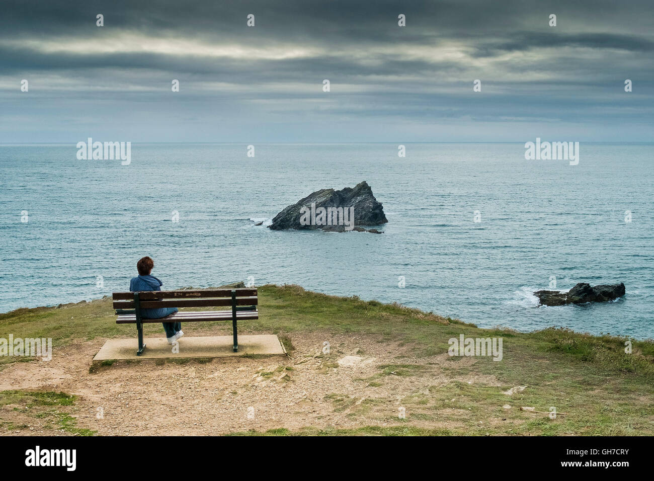 Une personne est assise sur un banc sur le Pointe Pentire à Newquay, Cornwall. Banque D'Images