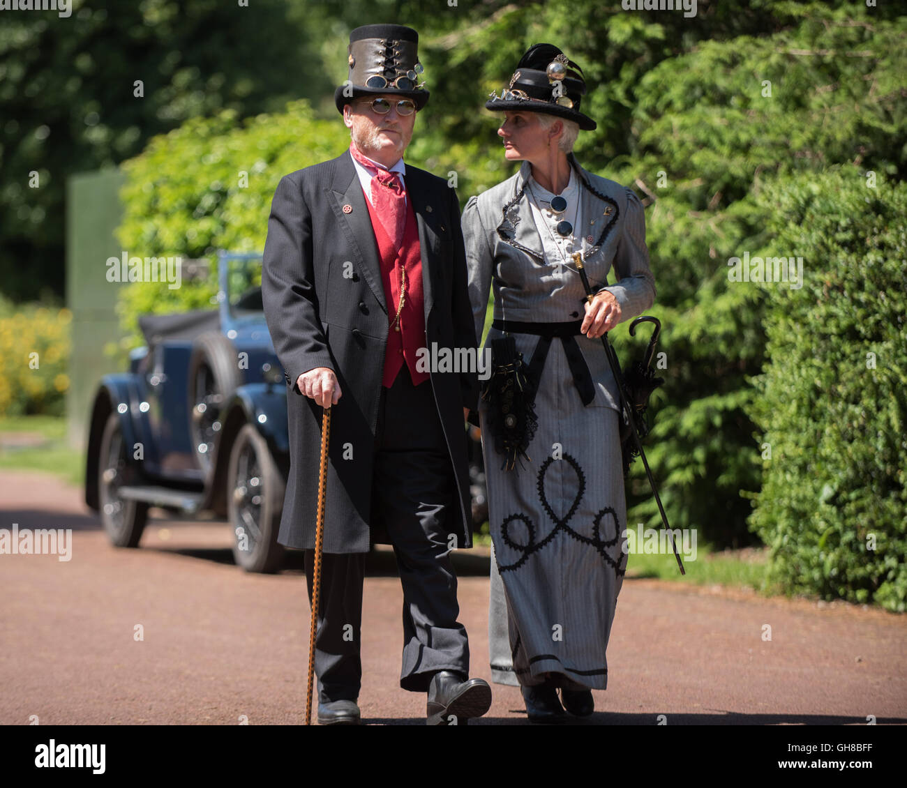 Homme et une femme parlant une promenade passant une voiture d'époque à papplewick événement steampunk des stations de pompage. Banque D'Images