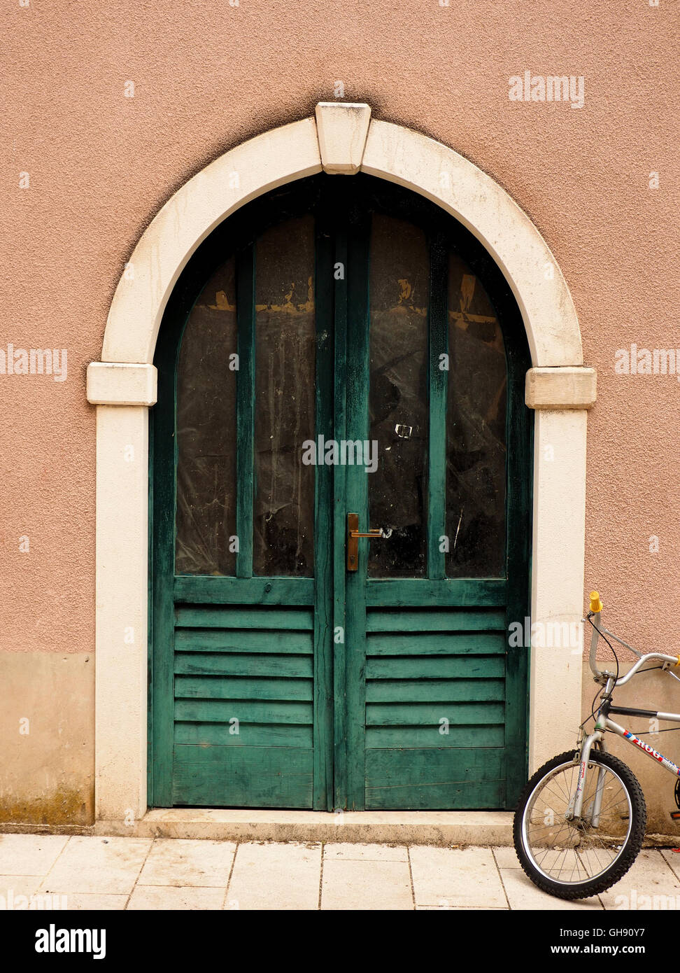 Location garée aux côtés de demi-persiennes vert double portes cintrées en blanc set porte en terre cuite de couleur couleur mur dans Dubrovnik Croatie Banque D'Images