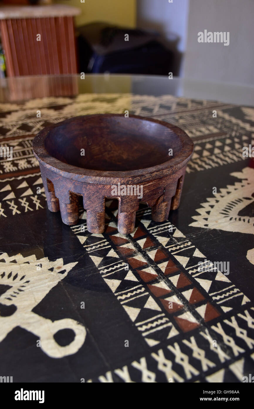 Tanoa Samoan antique ou laulau le kava bol sculpté dans du bois. Tapa Samoan chiffon sous verre sur table. Banque D'Images