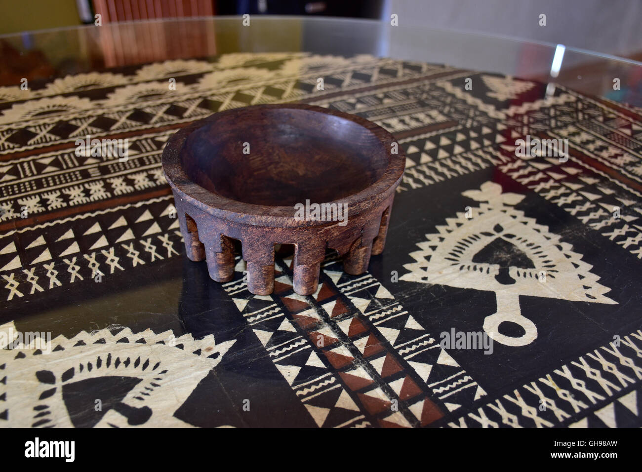 Tanoa Samoan antique ou laulau le kava bol sculpté dans du bois. Tapa Samoan chiffon sous verre sur table. Banque D'Images