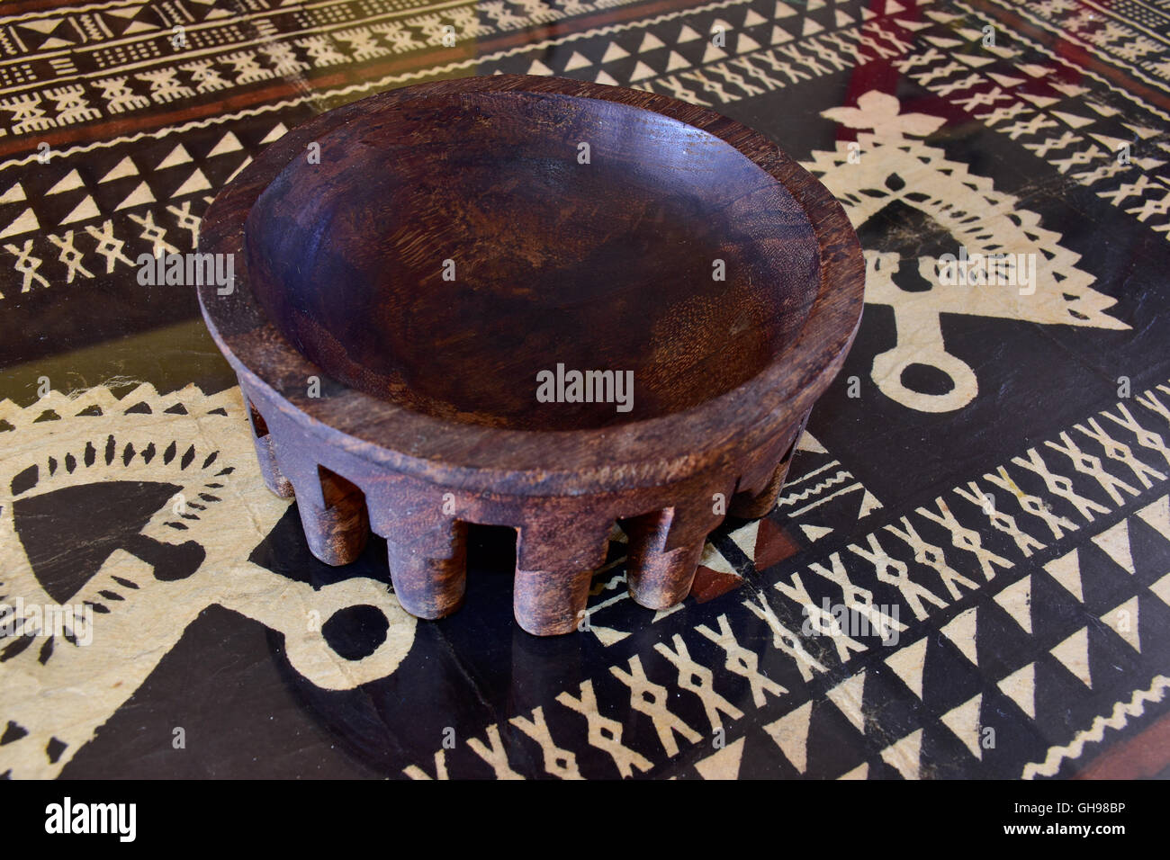 Tanoa Samoan antique ou laulau le kava bol sculpté dans du bois. Tapa Samoan chiffon sous verre sur table. Banque D'Images
