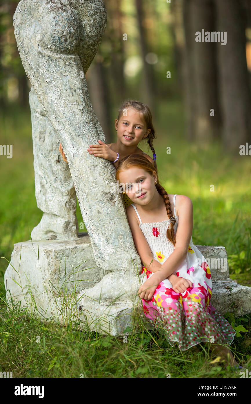 Deux mignonnes petites filles posant près de statue dans un parc. Banque D'Images