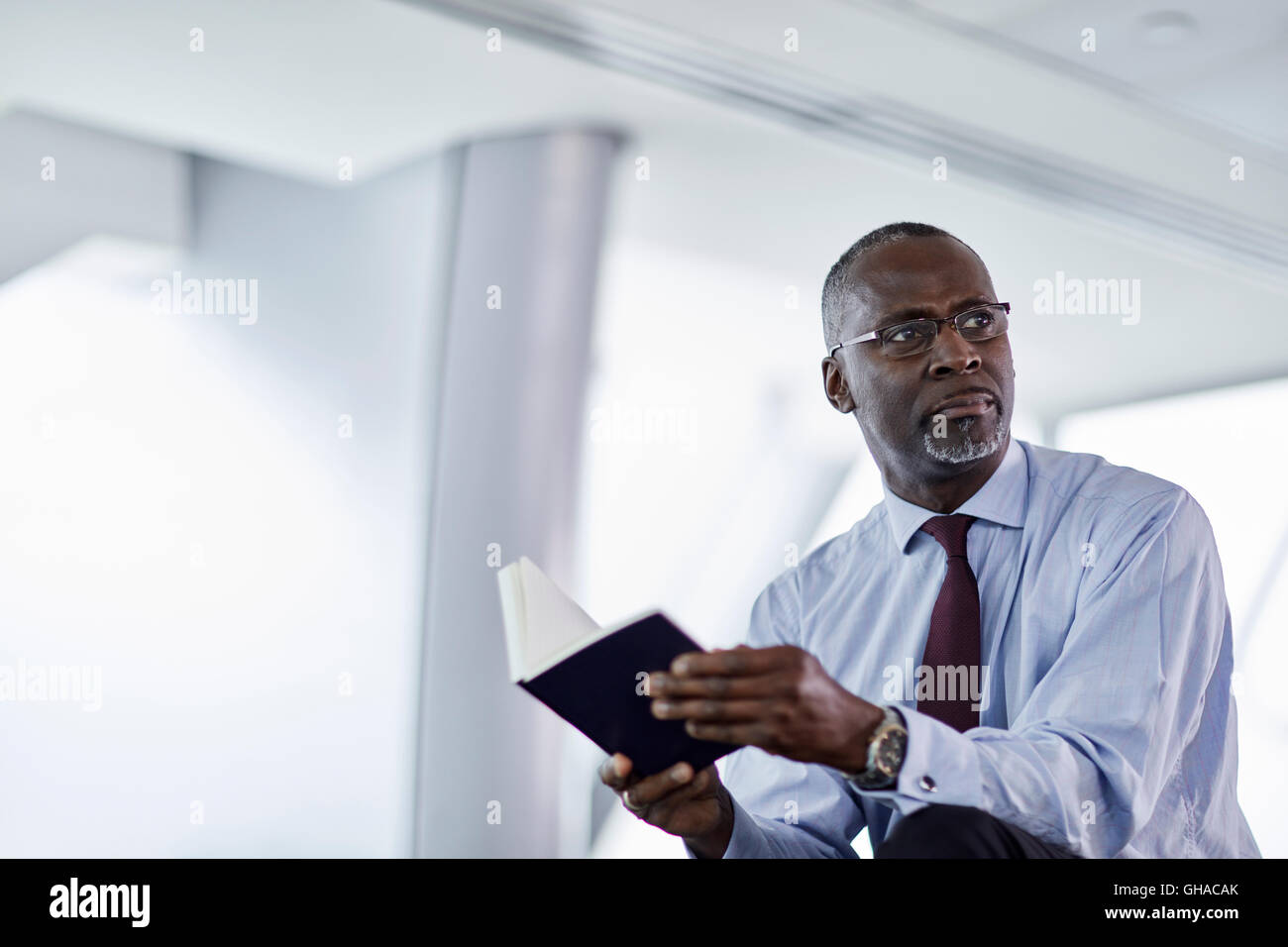 Pensive businessman avec journal looking away Banque D'Images