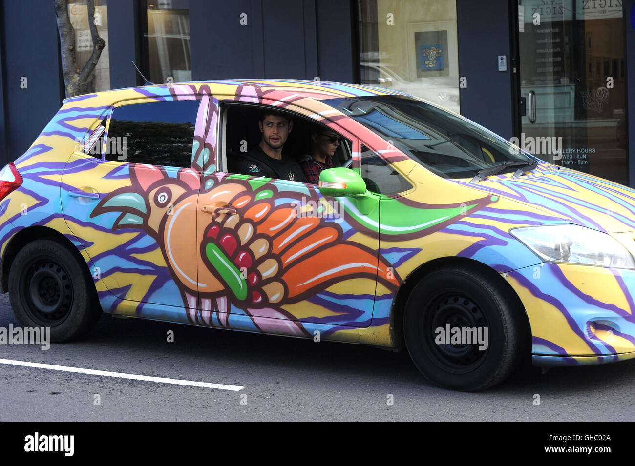 Un couple roulant en voiture de location colorés Banque D'Images