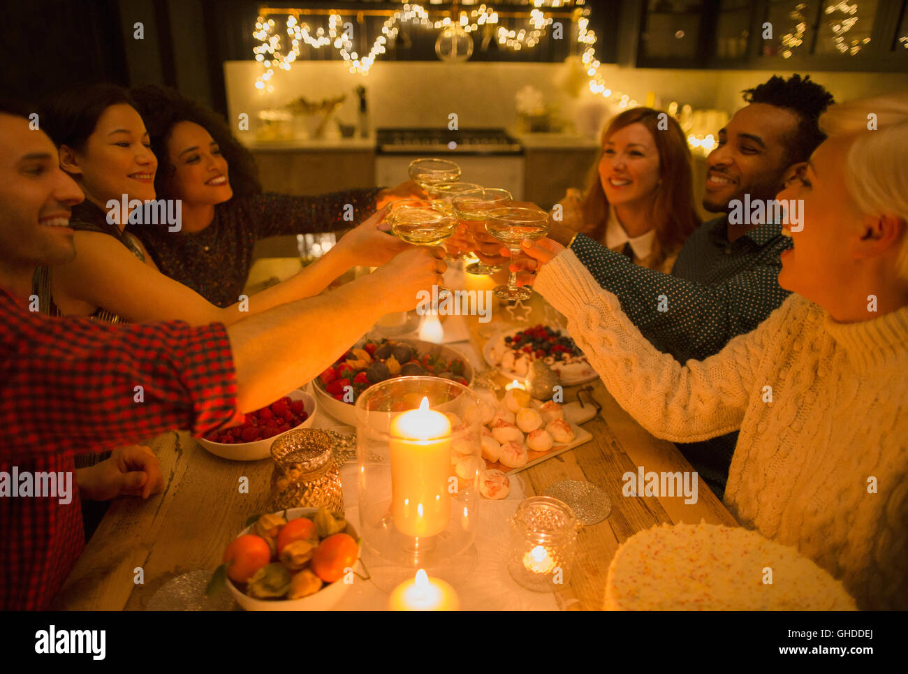 Friends toasting champagne verres à table aux chandelles Banque D'Images