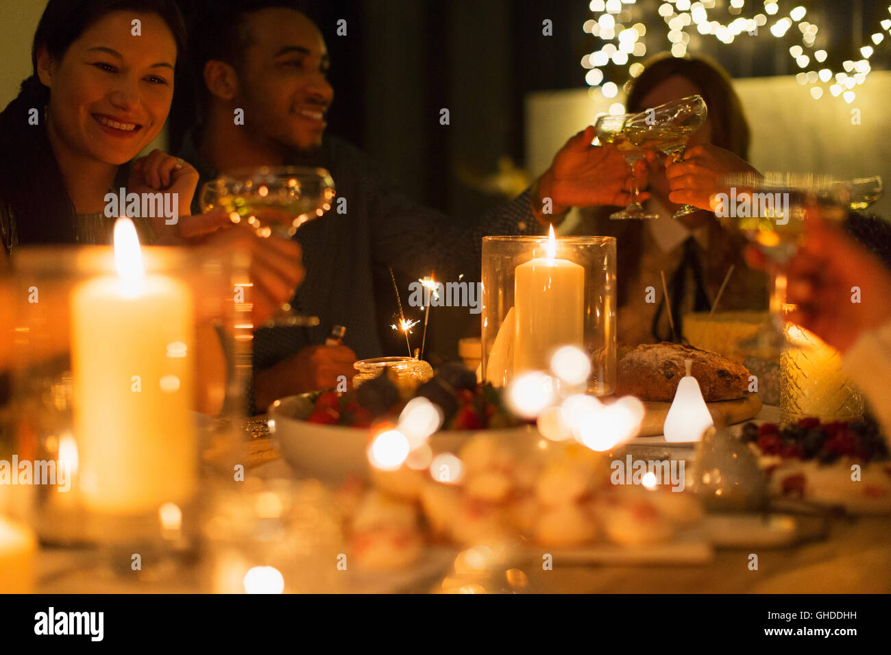Friends toasting champagne lunettes à la table de Noël aux chandelles Banque D'Images