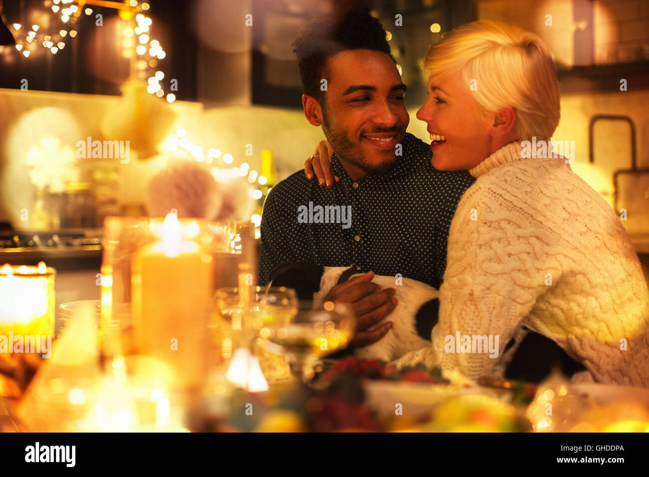 Affectionate couple avec chien à table de Noël aux chandelles Banque D'Images