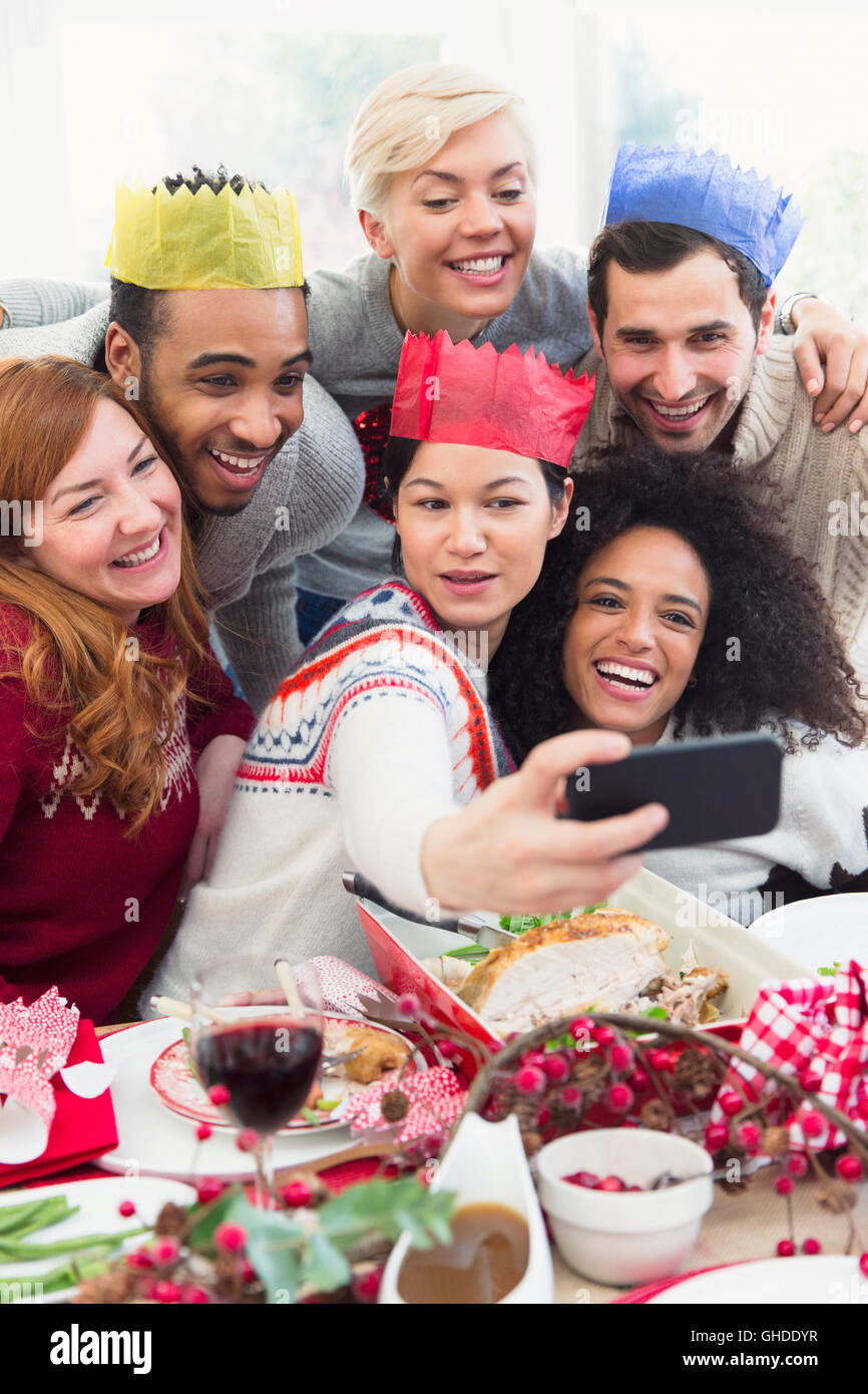 Amis de paper crowns en tenant au dîner de Noël selfies Banque D'Images