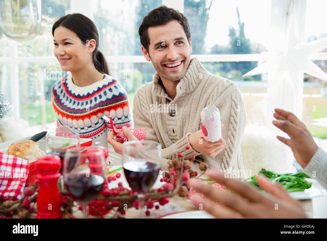 Smiling man holding Christmas Cracker at dinner table Banque D'Images