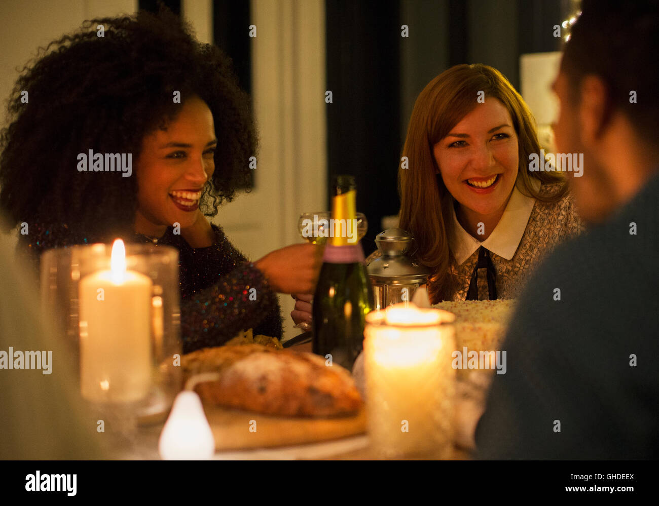 Smiling friends drinking champagne at candlelight dinner table Banque D'Images