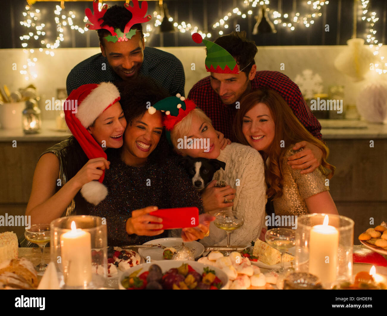 Amis ludique avec chien en tenant la chandelle à selfies table de Noël Banque D'Images
