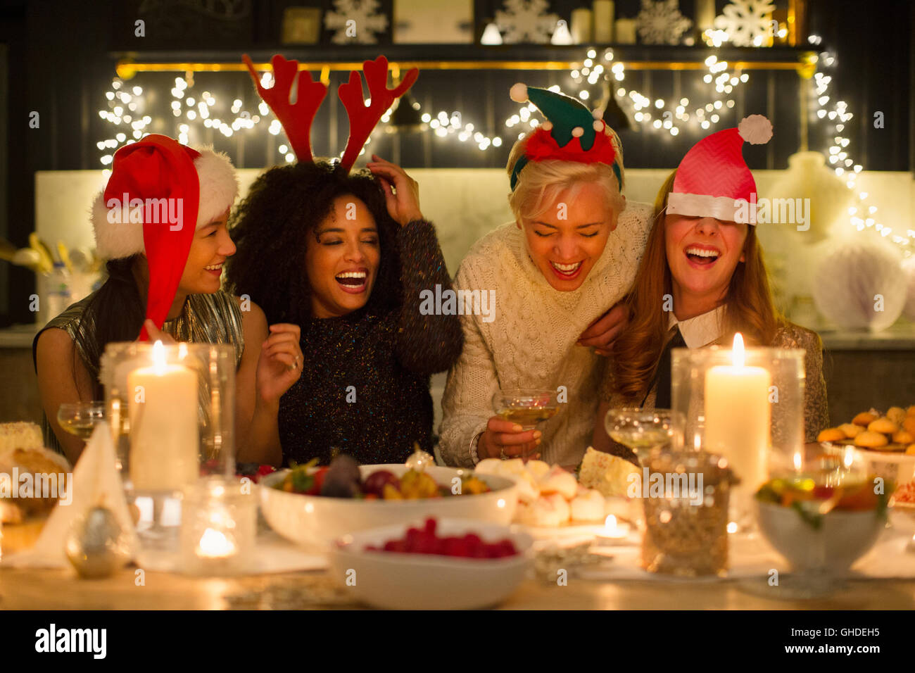 Laughing friends enjoying Christmas dinner aux chandelles Banque D'Images