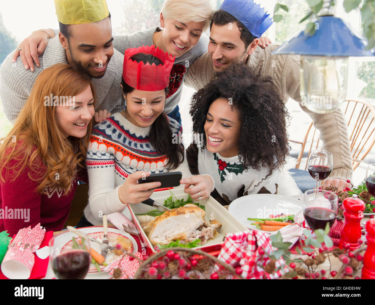 Les amis portant des couronnes de papier prendre le dîner de Noël à selfies Banque D'Images