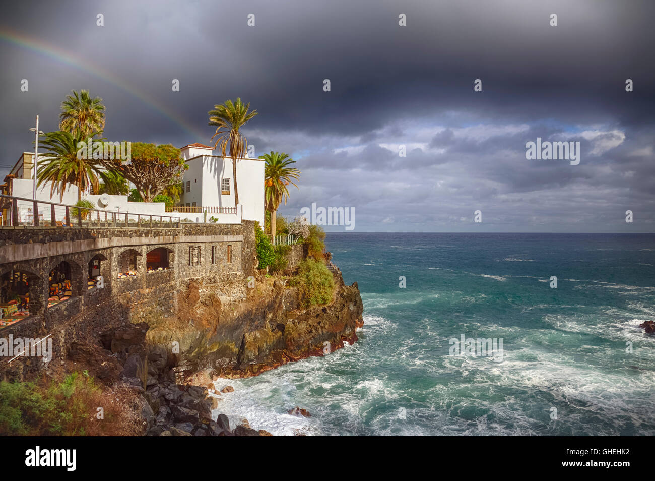 Hôtel de ville sur les rochers et les vagues de la mer sous un arc-en-ciel à Puerto de la Cruz, Tenerife, Espagne Banque D'Images