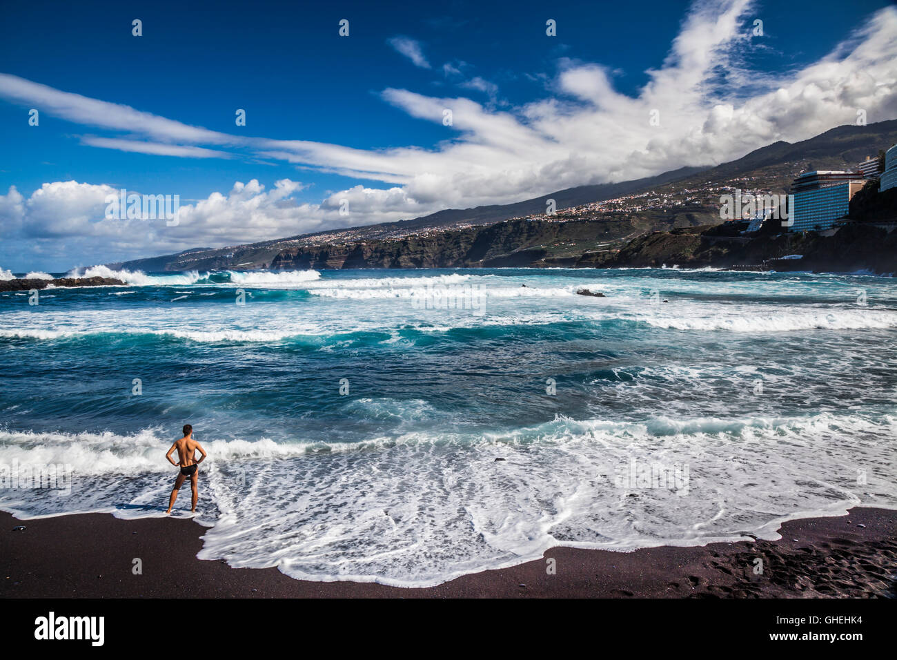 L'homme regardant les vagues brisant sur la plage de Puerto de la Cruz, Tenerfie, Espagne Banque D'Images