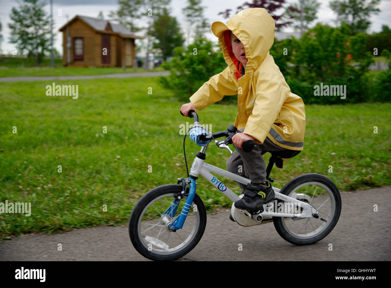 Un jeune garçon (4 ans) portant un imperméable jaune riding a bike Banque D'Images