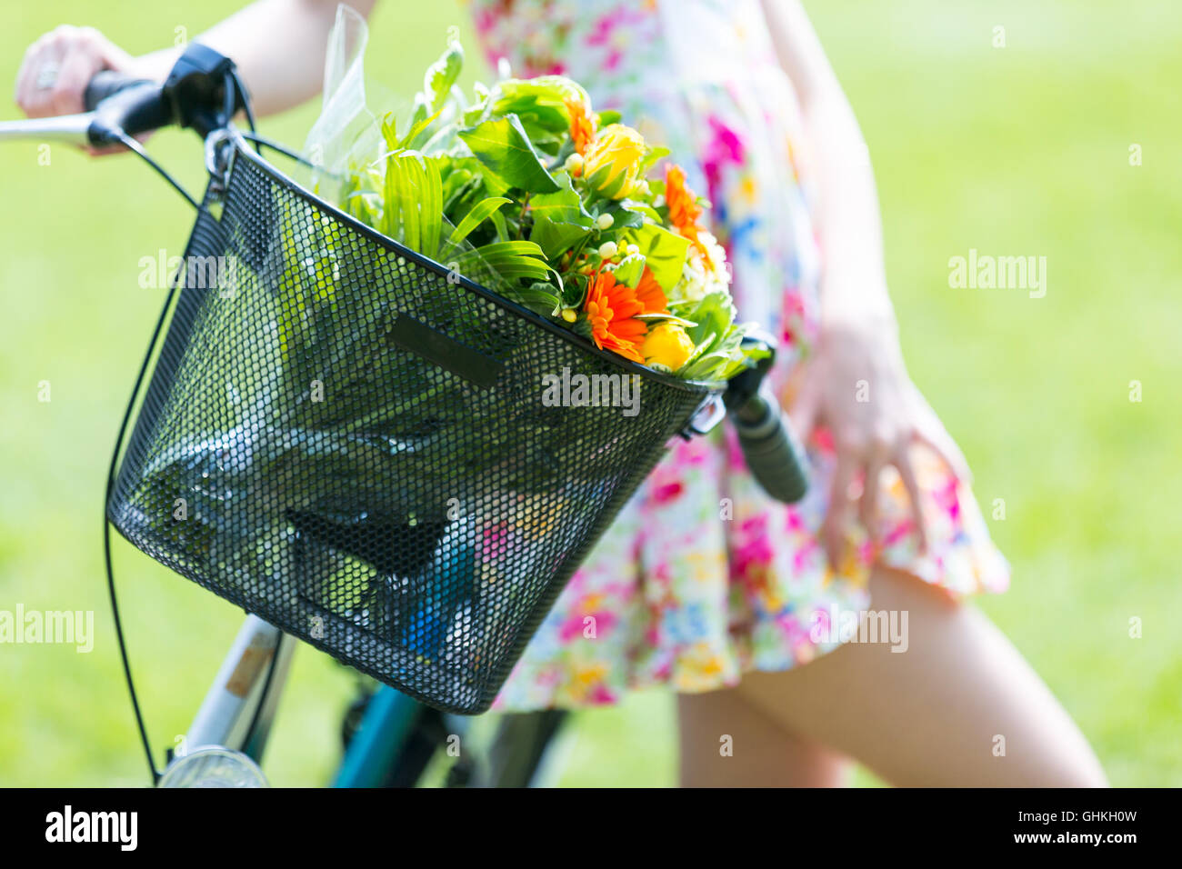 Jeune fille portant une robe d'été avec un bouquet de fleurs. Avec le vélo dans le parc Banque D'Images