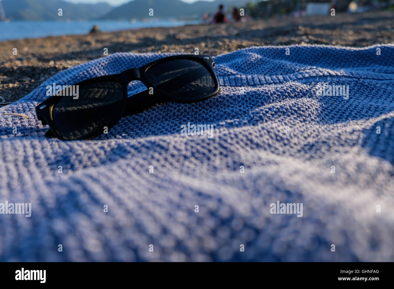 Lunettes de soleil sur une serviette bleue sur la plage Banque D'Images