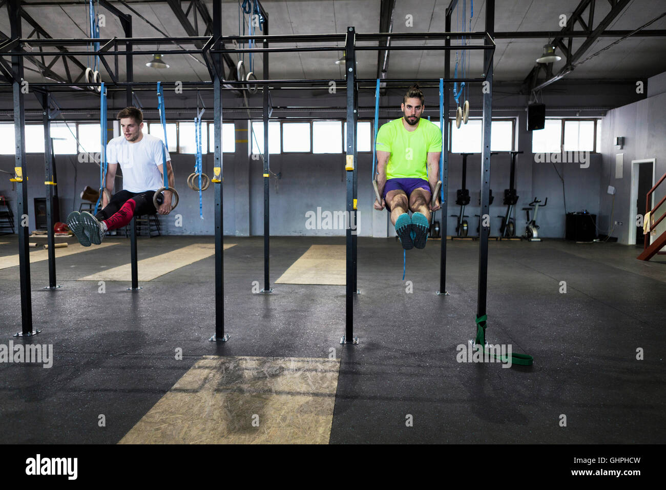 Deux hommes faisant l'exercice de gymnastique aux anneaux in gym Banque D'Images