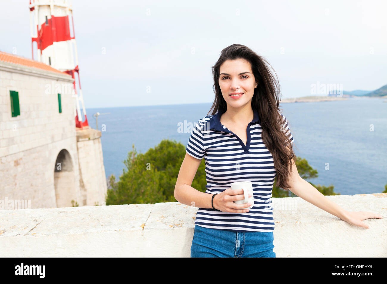 Jeune femme à boire le café au bord de la mer Banque D'Images