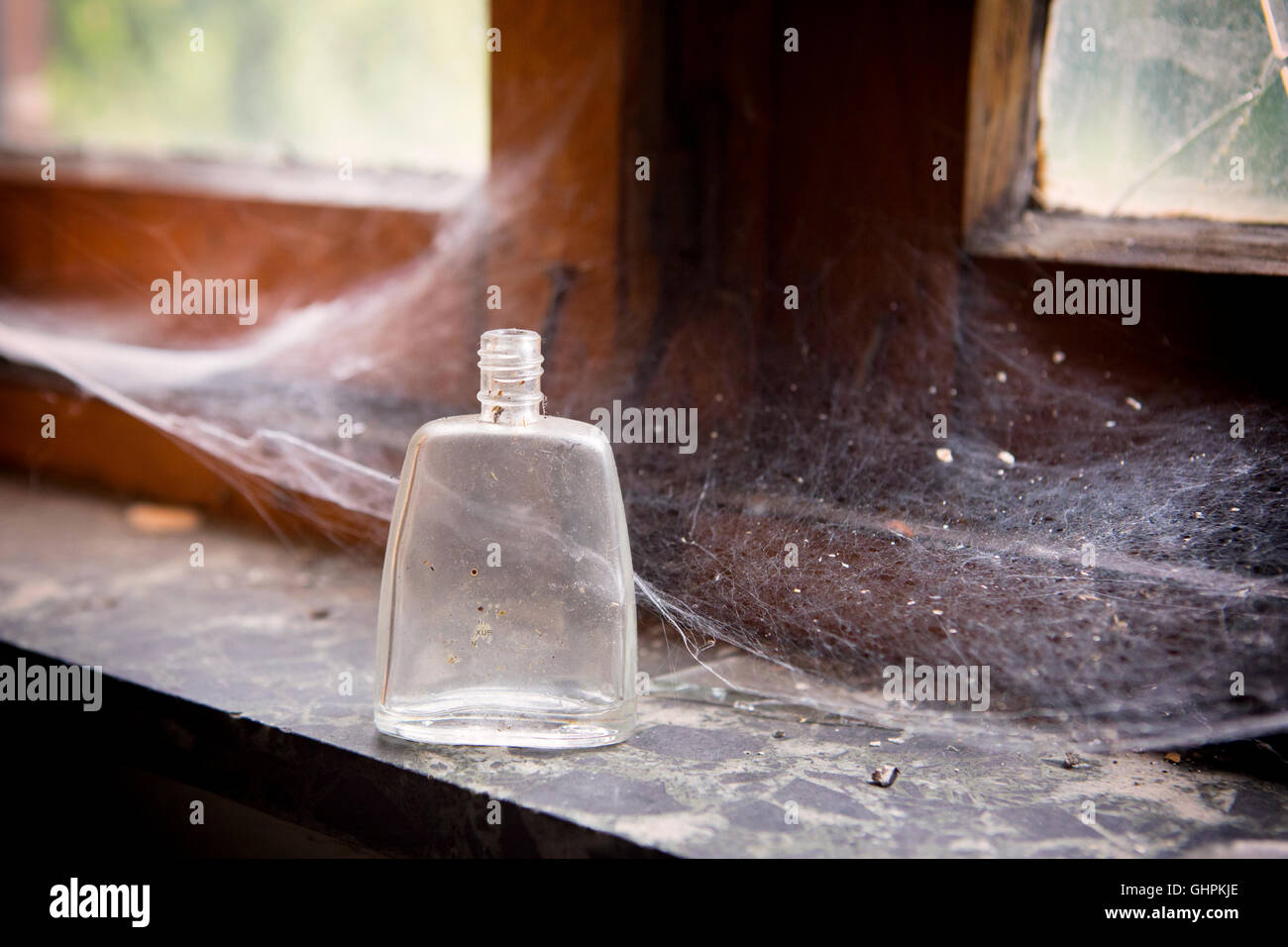 Vieille bouteille vide dans une fenêtre avec d'araignée Banque D'Images