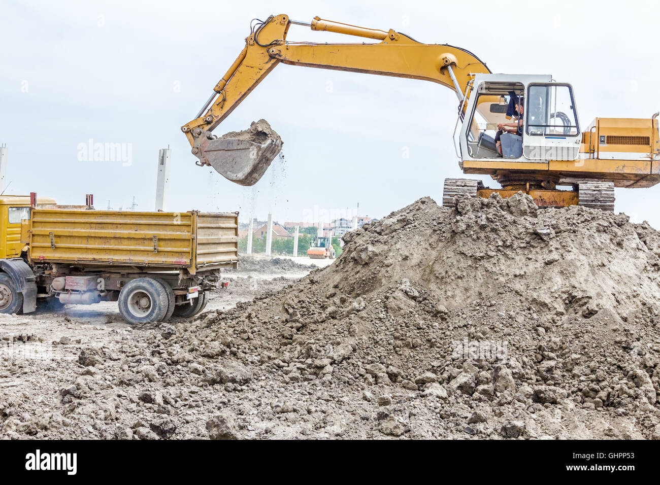Excavatrice jaune est le remplissage d'un camion à benne avec sol at construction site, projet en cours. Banque D'Images