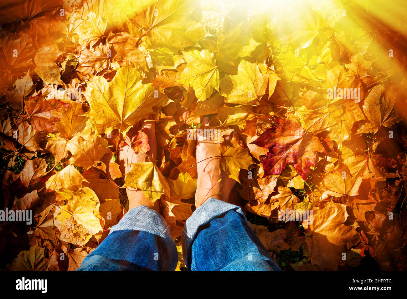 Homme debout pieds nus dans les feuilles d'automne Banque D'Images