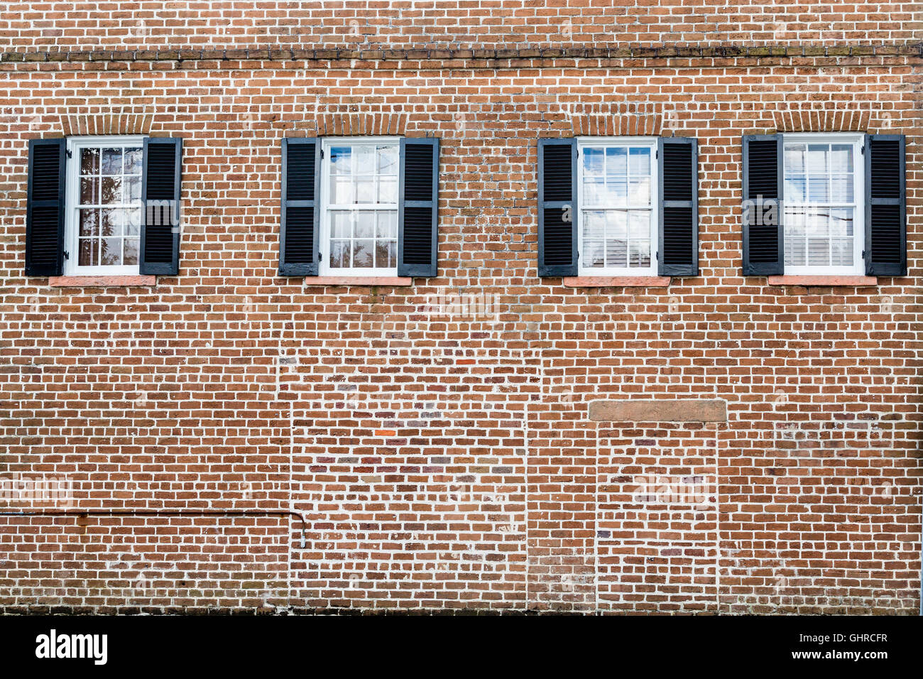 Volets noirs sur un vieux bâtiment en brique rouge Banque D'Images