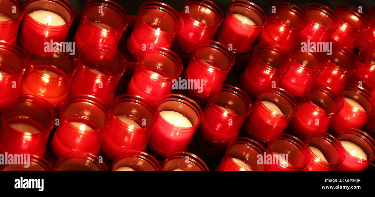 Beaucoup de flammes rouges de bougies allumées par les fidèles dans le lieu de culte au cours de la cérémonie religieuse Banque D'Images Beaucoup de flammes rouges de bougies allumées par les fidèles dans le lieu de culte au cours de la cérémonie religieuse Banque D'Images