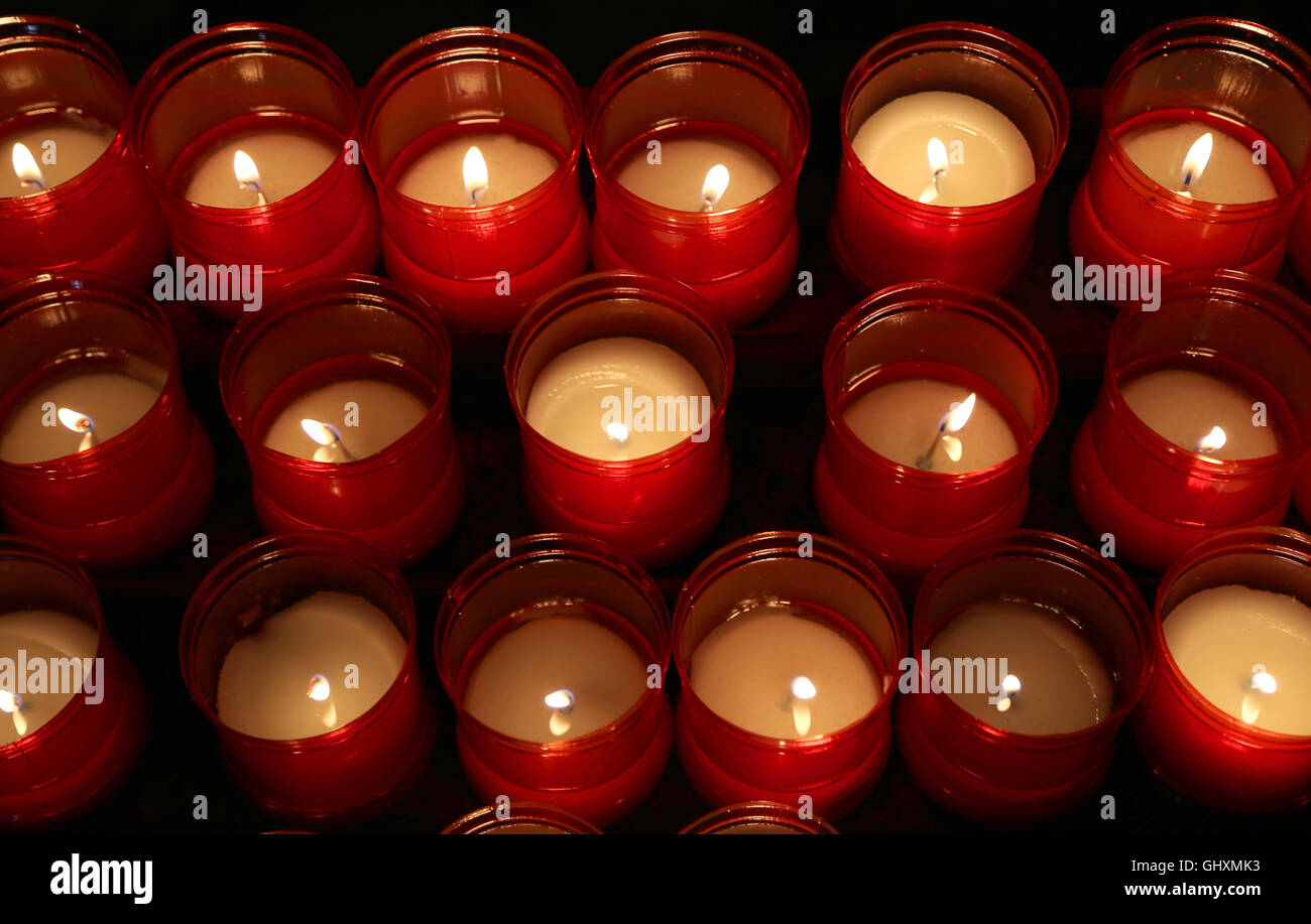 Série de flammes rouges de bougies allumées par les fidèles dans le lieu de culte au cours de la cérémonie religieuse Banque D'Images Série de flammes rouges de bougies allumées par les fidèles dans le lieu de culte au cours de la cérémonie religieuse Banque D'Images