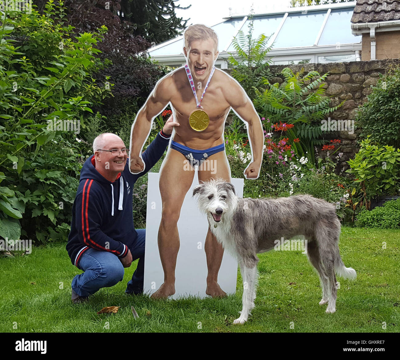 David rire, 52, et Alfie le chien avec un carton dentelle de son fils et médaillée d'or aux Jeux Olympiques, qui a rire Jack en plaisantant que son triomphe était parce qu'il n'était pas là à Rio de le mettre hors tension. Banque D'Images