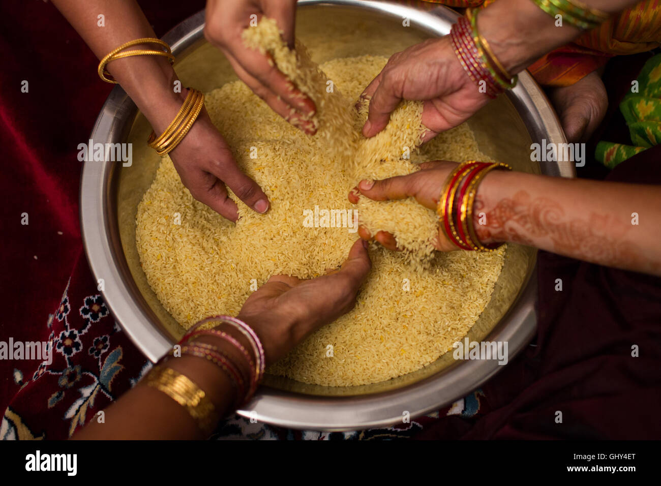 Les femmes indiennes riz mélange avec le curcuma pour être utilisé dans les rituels hindous au cours de mariage Banque D'Images