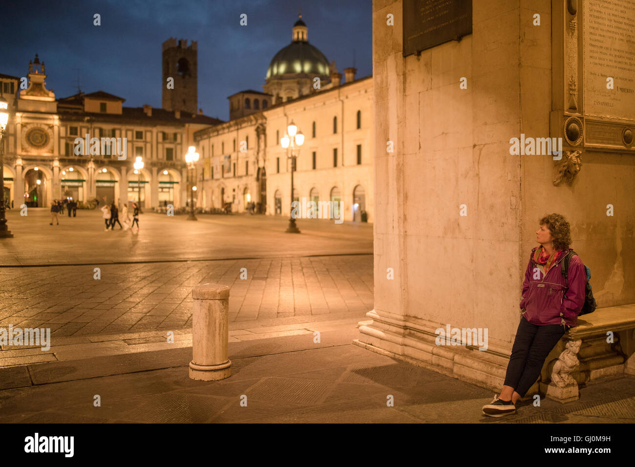 Wendy en attente dans la Piazza della Loggia au crépuscule, Brescia, Lombardie, Italie Banque D'Images