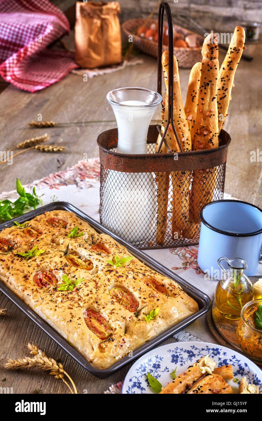 Focaccia traditionnel avec des tomates et des bâtonnets de pain rustique, sur une table en bois. Banque D'Images