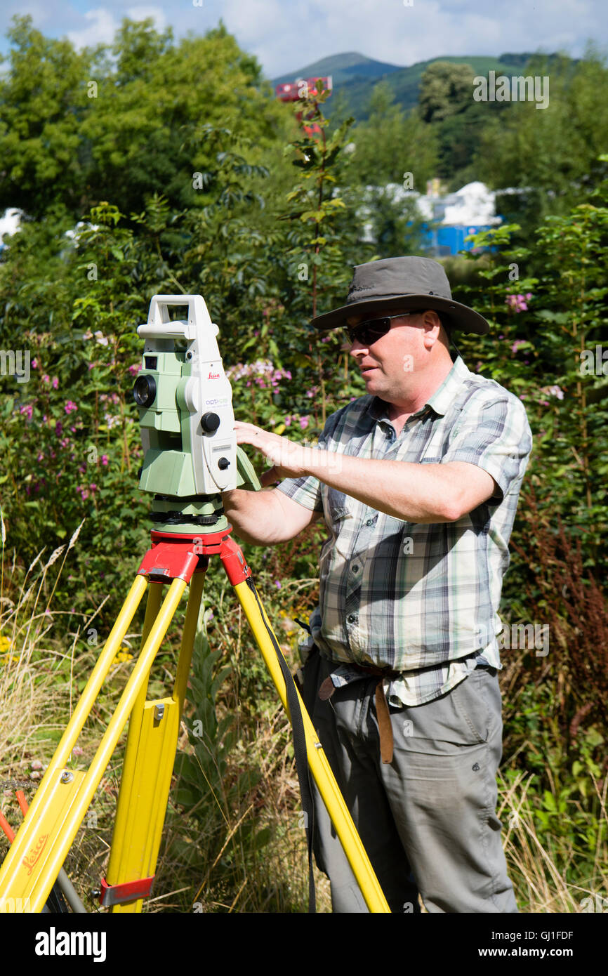 Un arpenteur professionnel à l'aide d'un théodolite numérique Leica Opti-Cal land survey et l'outil de mesure de précision sur un trépied à mesaure la quantité de mouvement du sol et des terres à proximité d'un développement du logement à Abergavenny, Monmouthsire Wales UK Banque D'Images