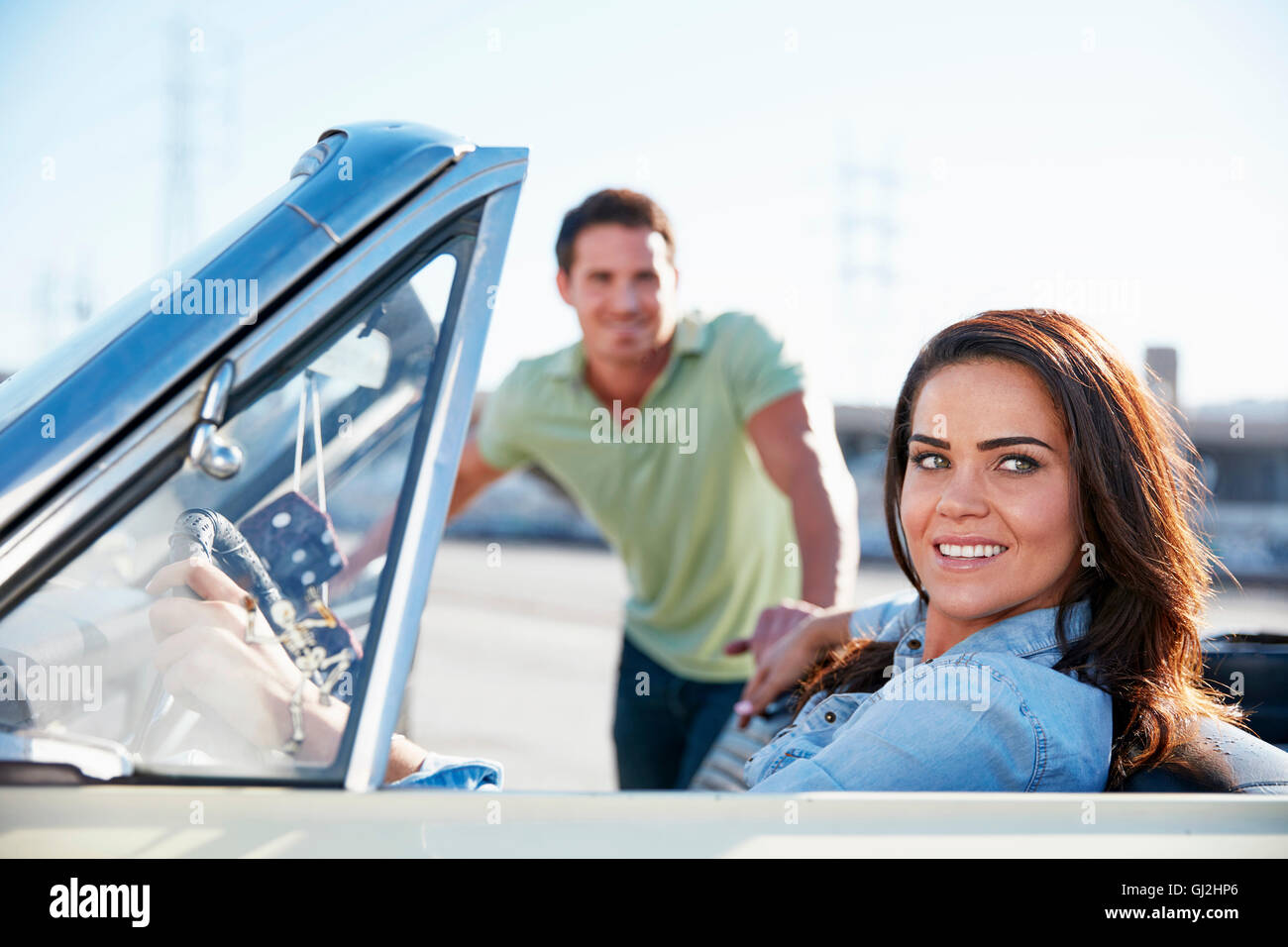 Woman sitting in convertible car, l'homme debout à côté de voiture Banque D'Images