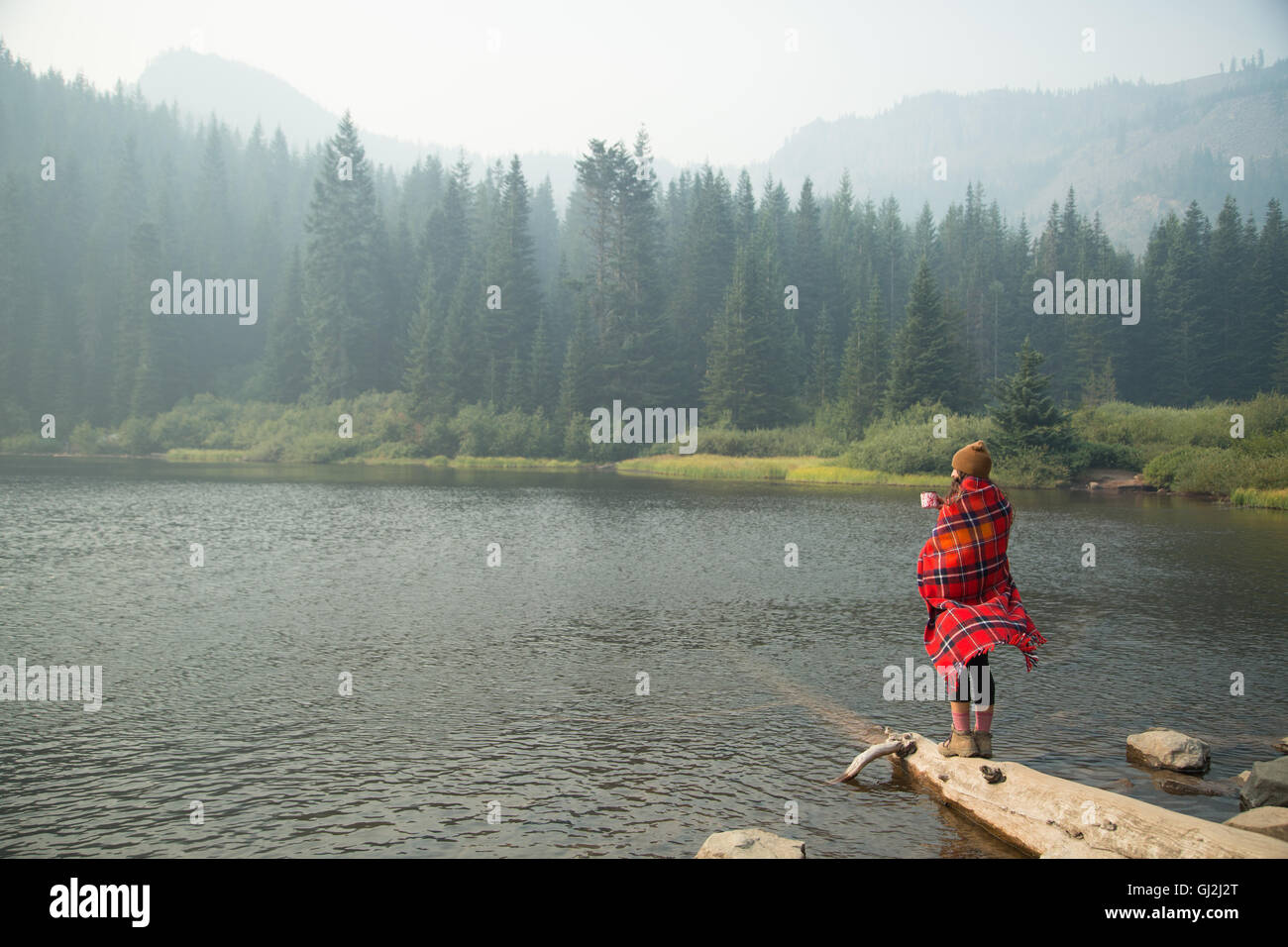 Femme enveloppée dans une couverture tartan boire du café par Misty Lake, Mount Hood National Forest, North Carolina, USA Banque D'Images Femme enveloppée dans une couverture tartan boire du café par Misty Lake, Mount Hood National Forest, North Carolina, USA Banque D'Images