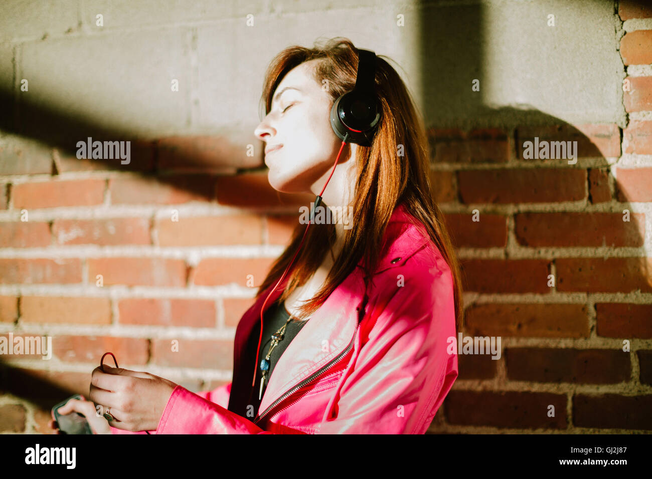 Jeune femme portant des écouteurs les yeux fermés smiling Banque D'Images