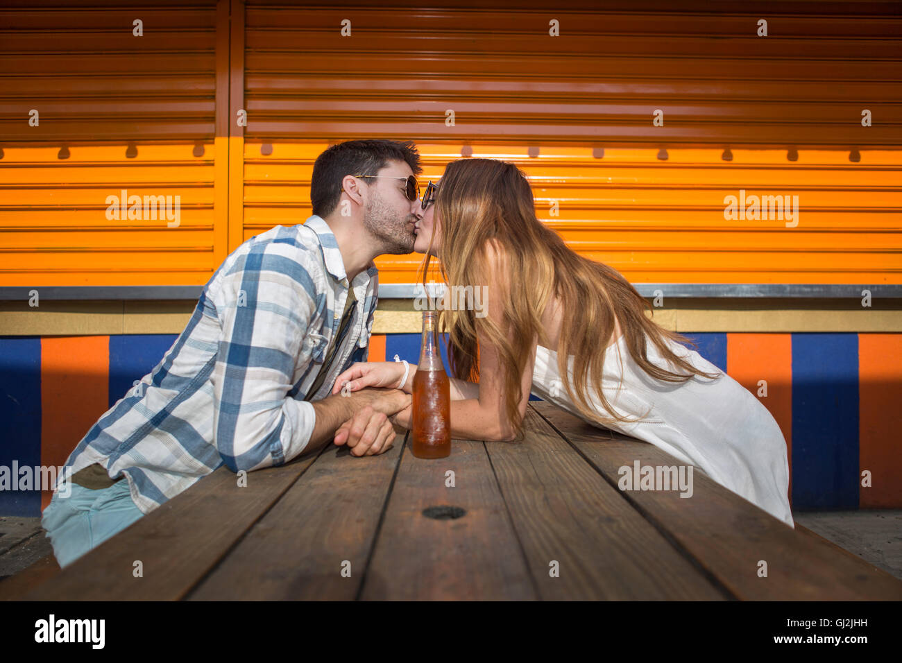 Couple assis face à face à une table de pique-nique à l'embrasser, à Coney Island, Brooklyn, New York, USA Banque D'Images