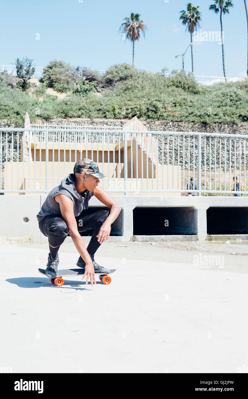 Woman crouching on skateboard Banque D'Images