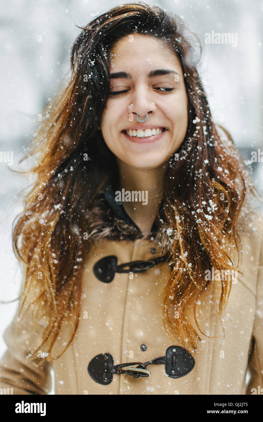 Duffle coat femme portant dans la neige, les yeux fermés, smiling Banque D'Images