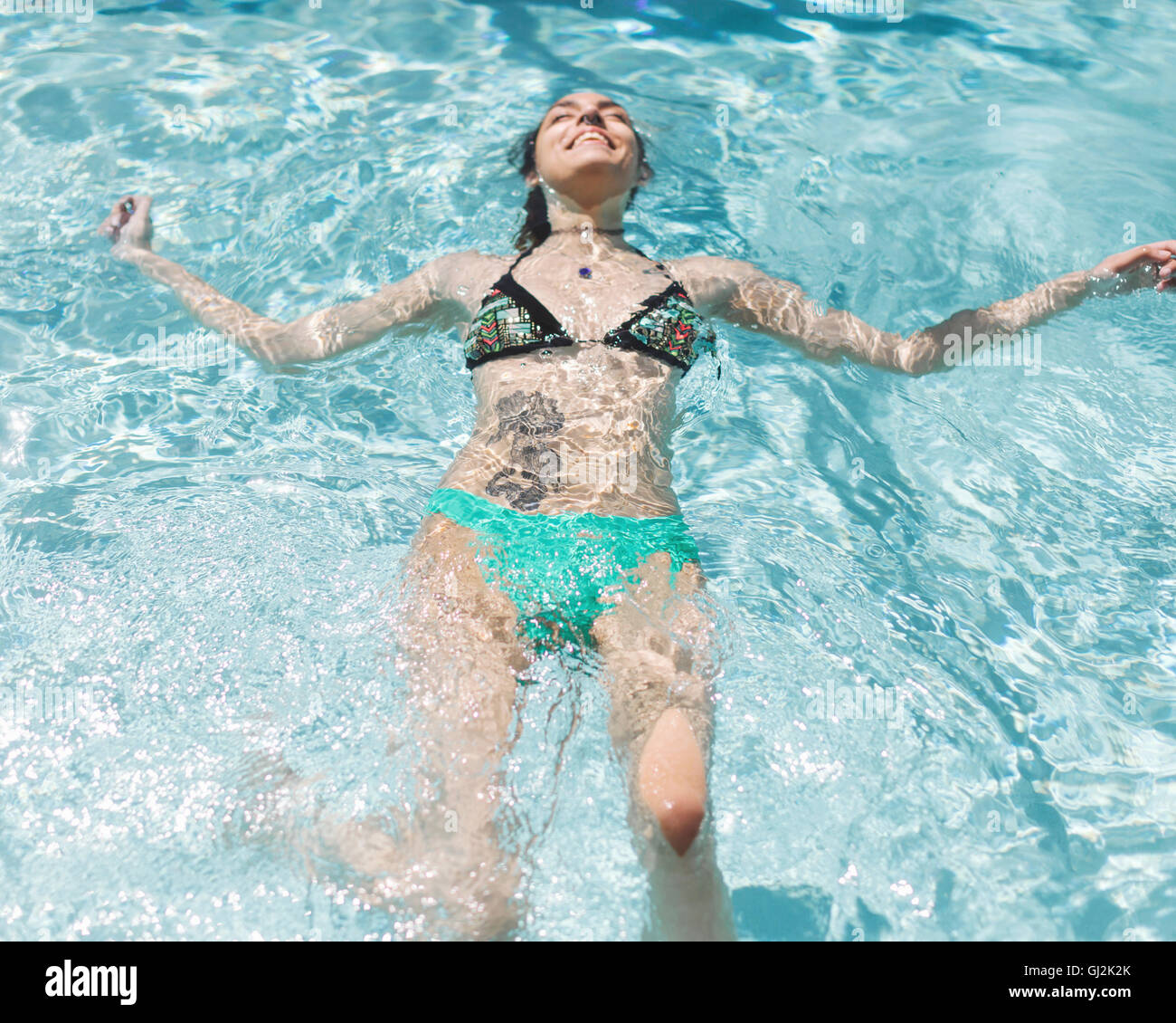 Woman floating in pool Banque D'Images