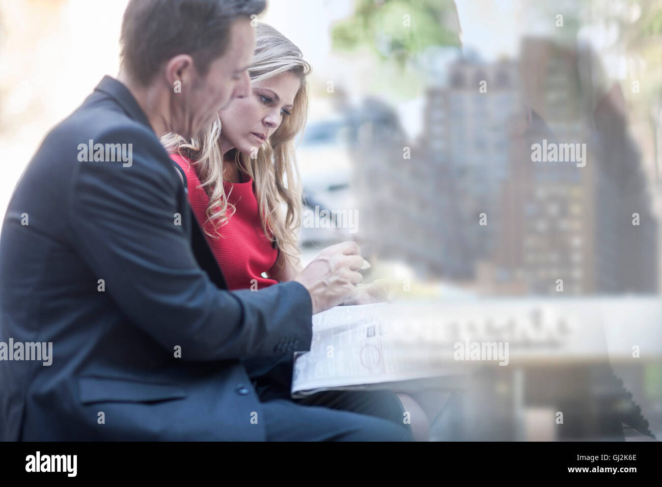 Businessman and woman reading newspaper et bavarder dans city park Banque D'Images