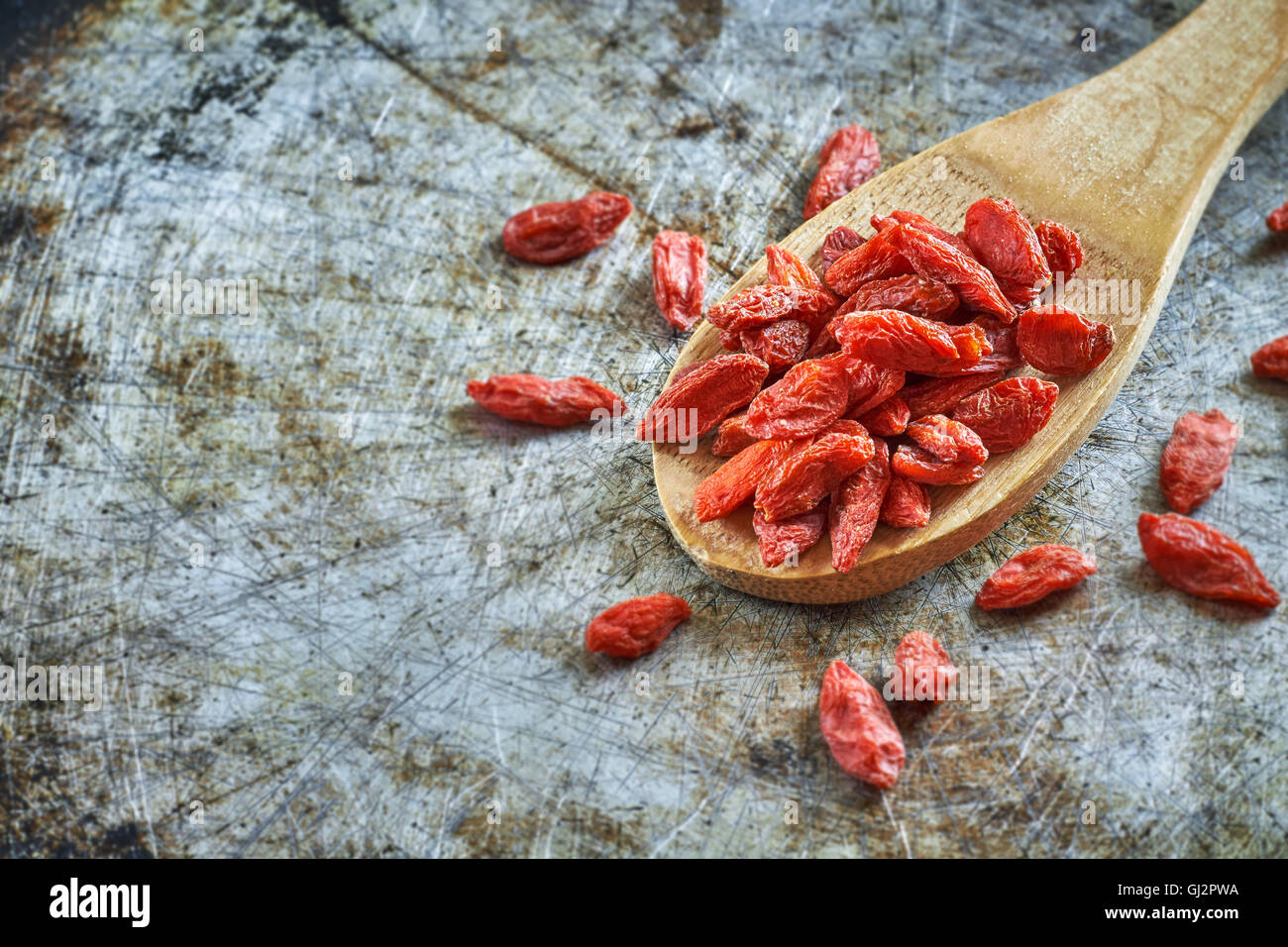 Baies de goji séchées en cuillère en bois rustique sur fond métallique. Copy space Banque D'Images