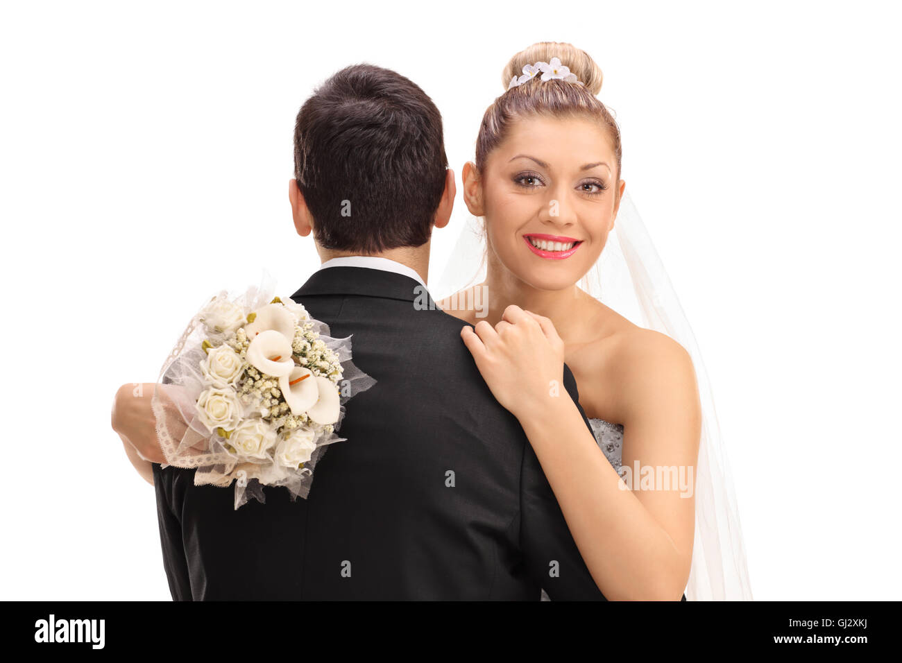 Happy young bride hugging groom et tenant un bouquet dans sa main isolé sur fond blanc Banque D'Images