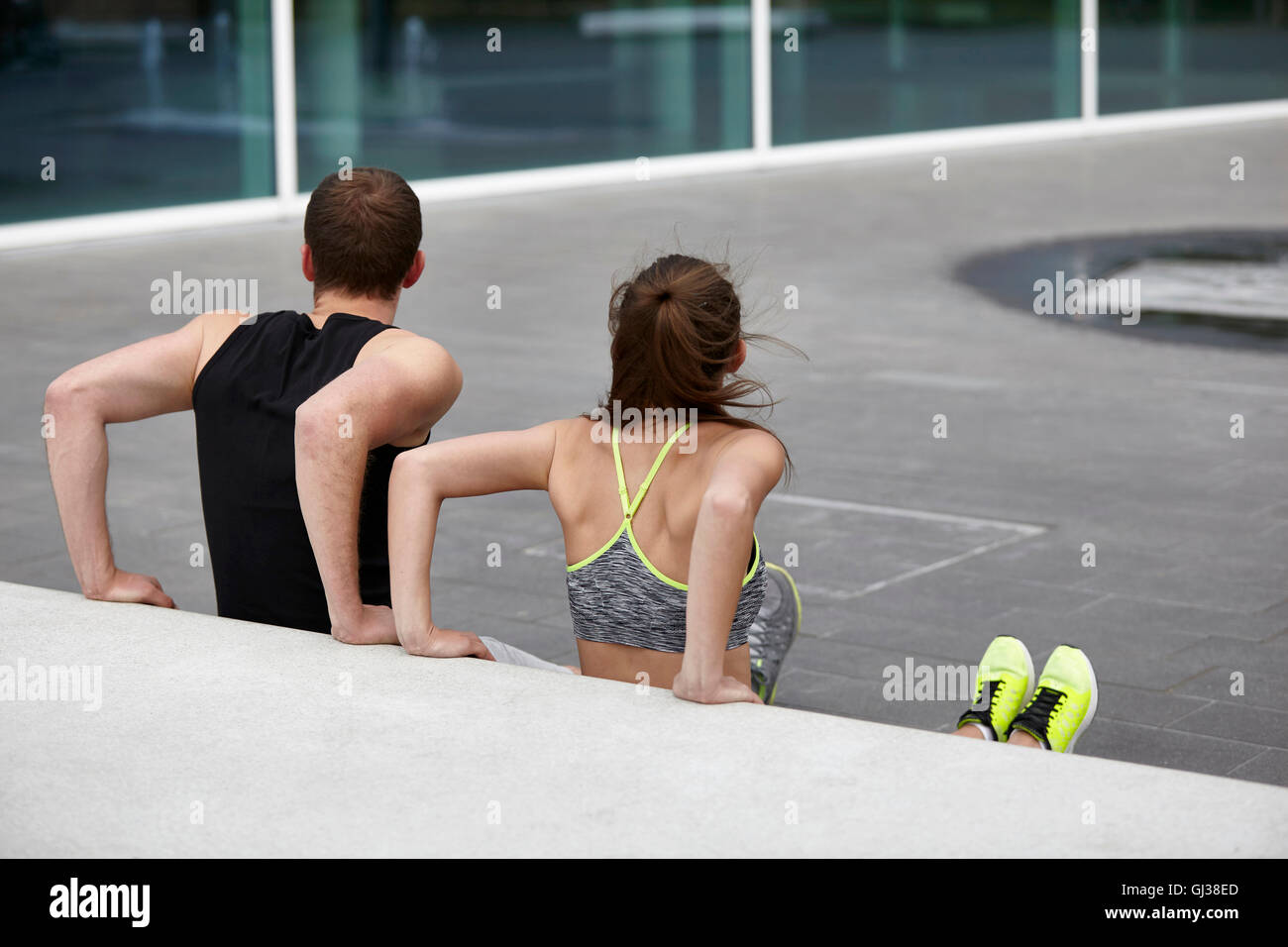 Jeune femme et homme de la formation, de faire poussez se lève contre le mur Banque D'Images