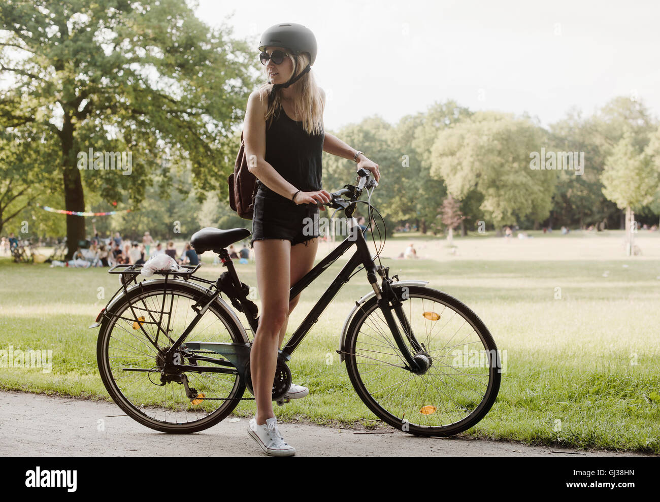 Jeune femme en parc, prépare à circuler à bicyclette Banque D'Images