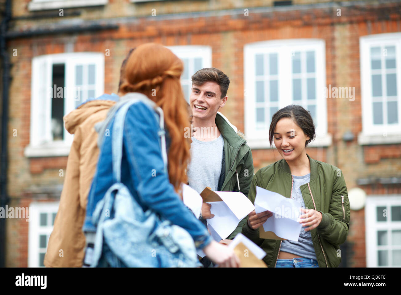 Heureux homme et femme college students reading résultats d'examen sur le campus Banque D'Images